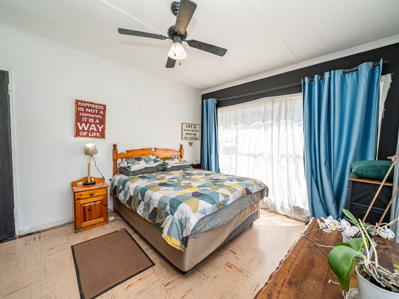A bedroom featuring a ceiling fan and vinyl flooring, offering a functional space with potential for cosmetic updates.