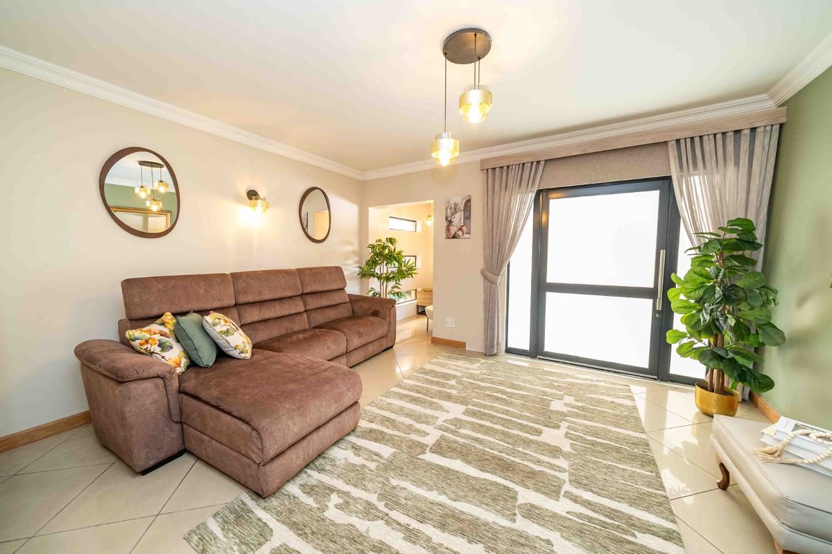 A well-maintained living room featuring tiled flooring, crown molding, and a large sliding glass door that provides access to the exterior.