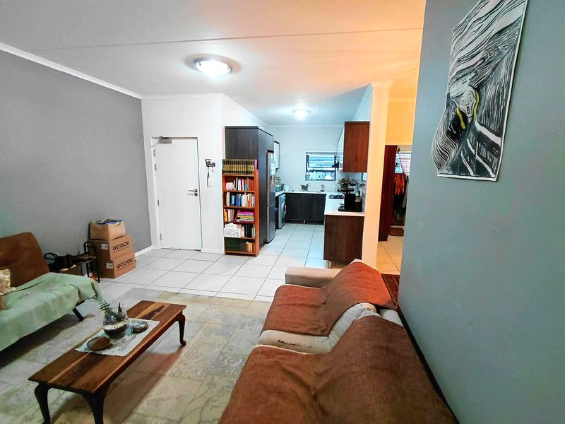 Open plan living area featuring tiled flooring and a functional kitchen with built-in cabinetry, creating a connected and versatile living space.