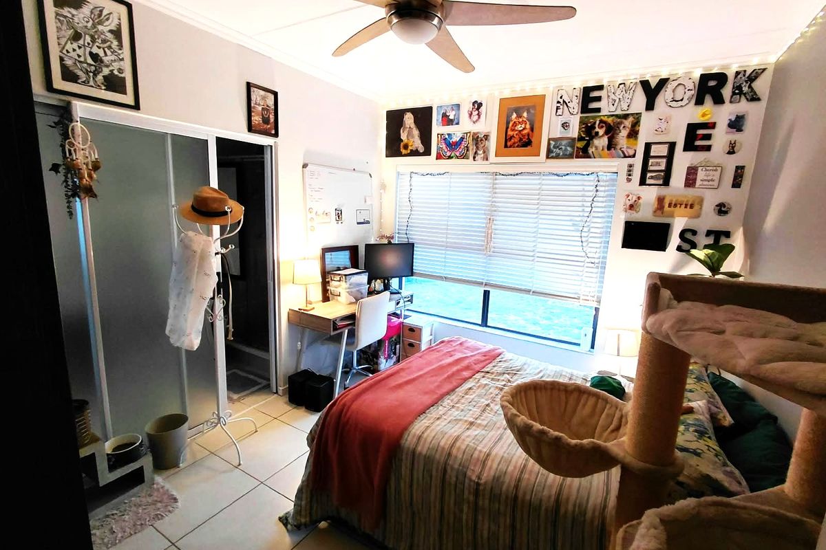 A bedroom featuring tiled flooring, a ceiling fan, and a sliding door wardrobe with an adjacent en-suite bathroom entrance.