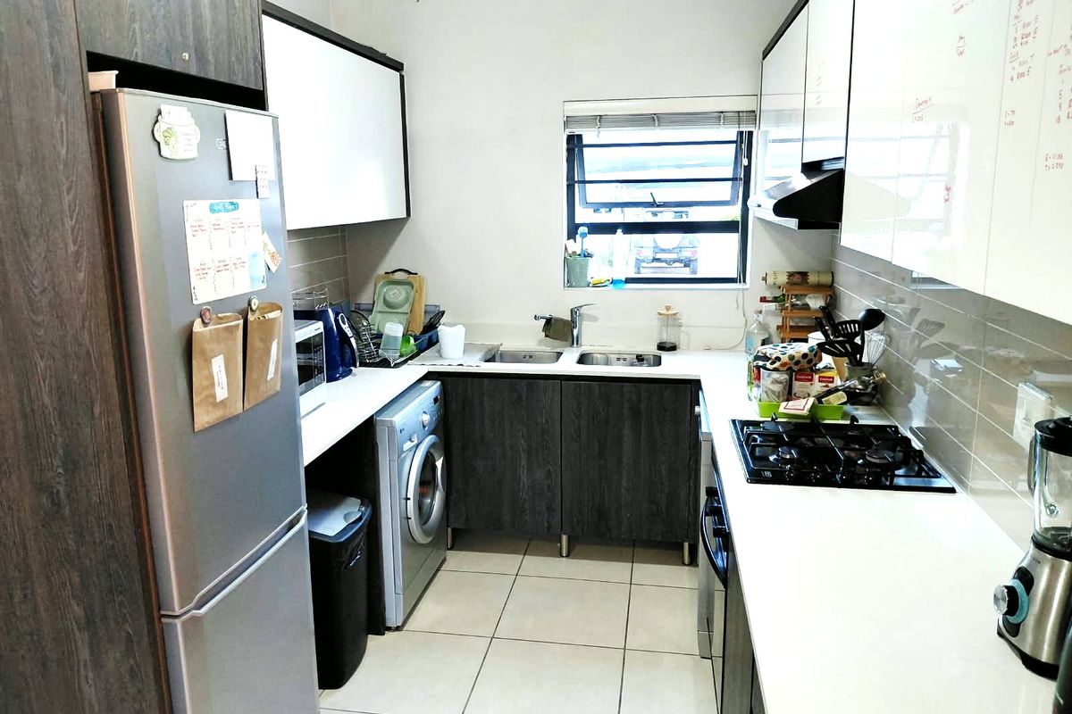 Compact kitchen featuring modern two-tone cabinetry, gas hob, extractor fan, double sink, and tiled flooring with a functional layout.