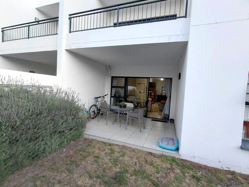 A ground floor patio area featuring tiled flooring and a sliding glass door providing access to the apartment interior.