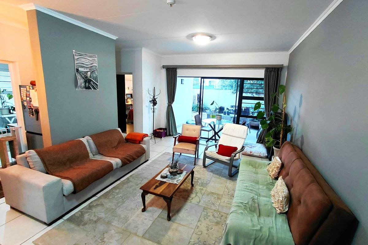 Spacious living room featuring tiled flooring and large sliding glass doors that provide access to an outdoor patio area.