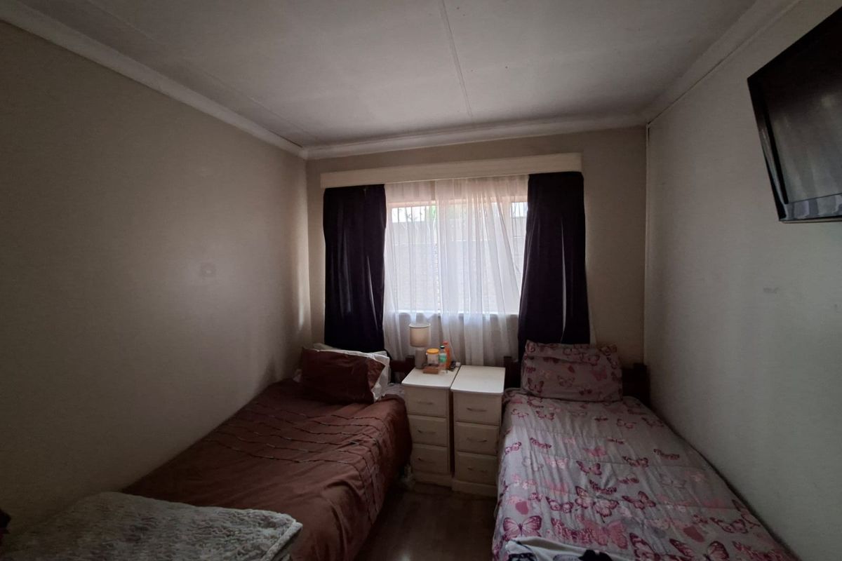 A functional bedroom featuring neutral wall finishes and a window with curtain treatments.