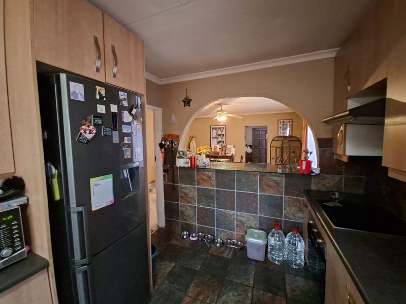 A functional kitchen featuring tiled flooring, a breakfast bar with a tiled facade, and an arched opening leading to the adjacent living area.