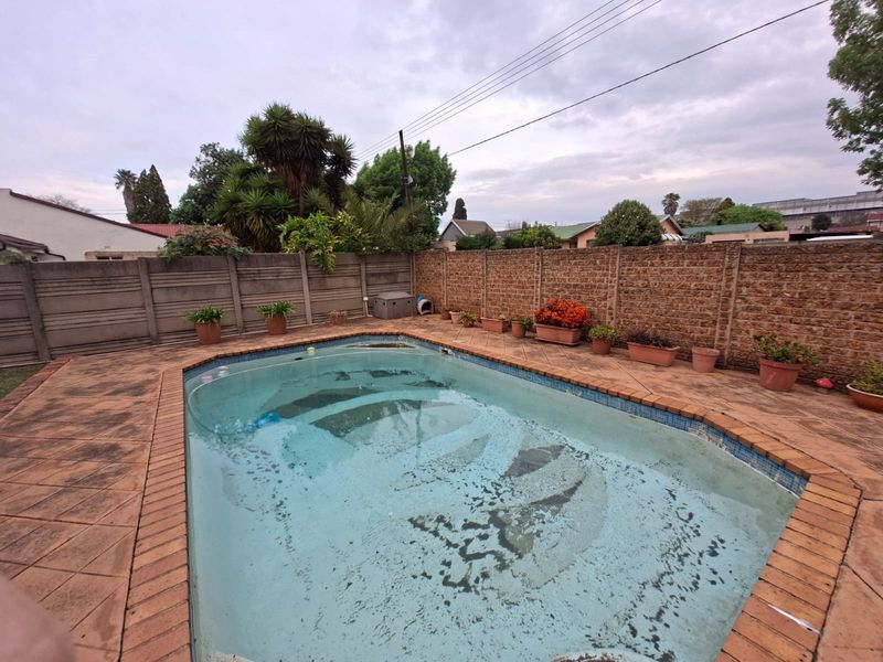 Outdoor pool area featuring a swimming pool with paved surround and perimeter boundary walls.