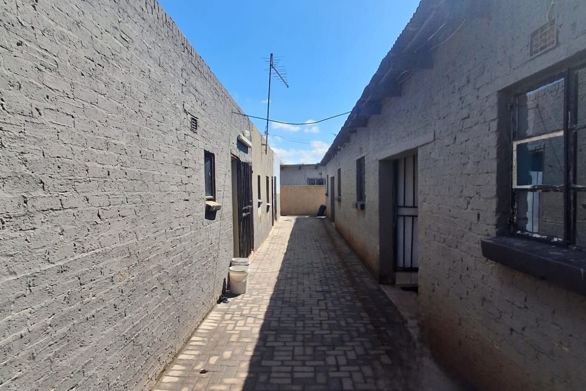 A narrow exterior side passage featuring brick paving and exposed brick walls connecting different sections of the property.