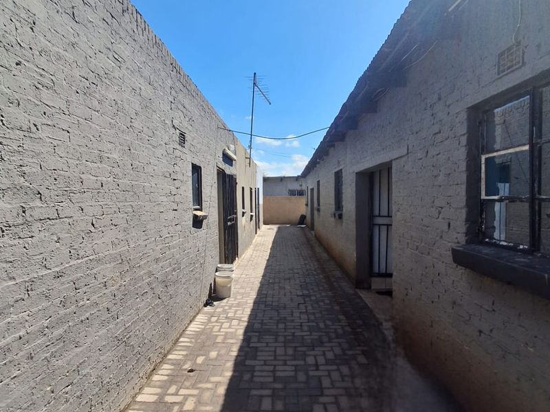 A narrow exterior side passage featuring brick paving and exposed brick walls connecting different sections of the property.
