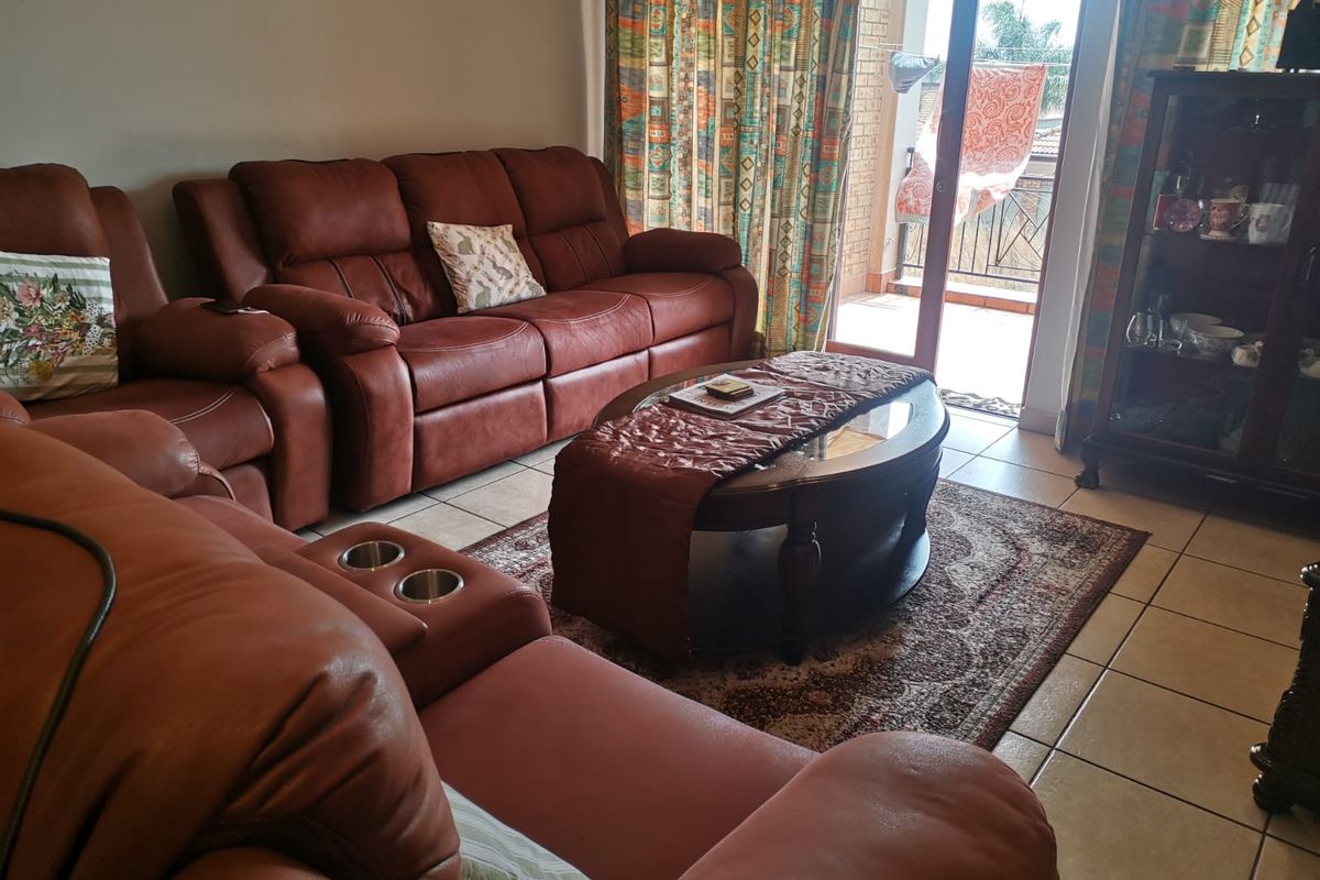 A living room area featuring tiled flooring and a sliding glass door providing access to an outdoor balcony space.