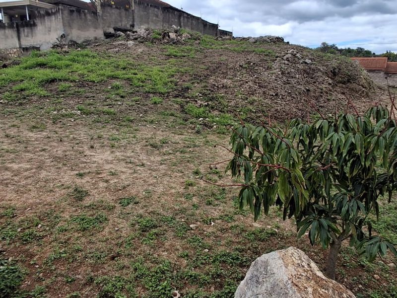 A view of the sloped, undeveloped residential land featuring a retaining wall at the upper boundary.