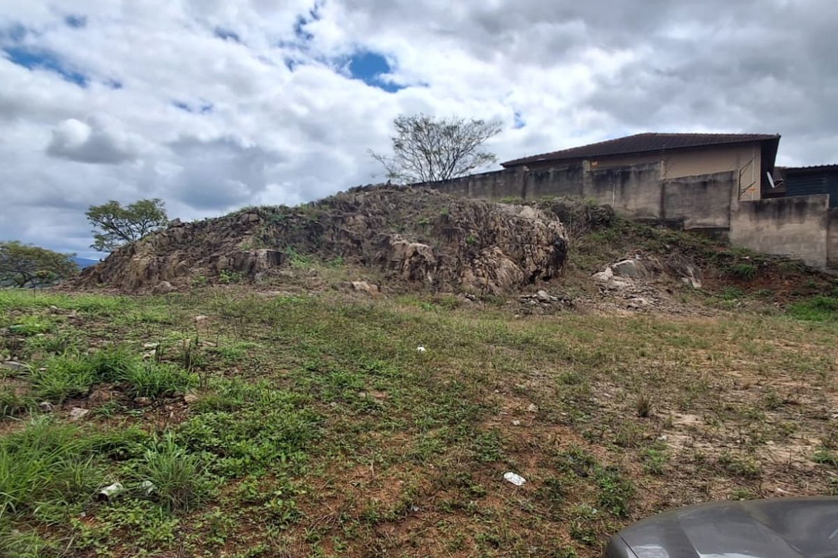 A view of the rear portion of the vacant residential land featuring a natural rock outcrop and a boundary retaining wall.