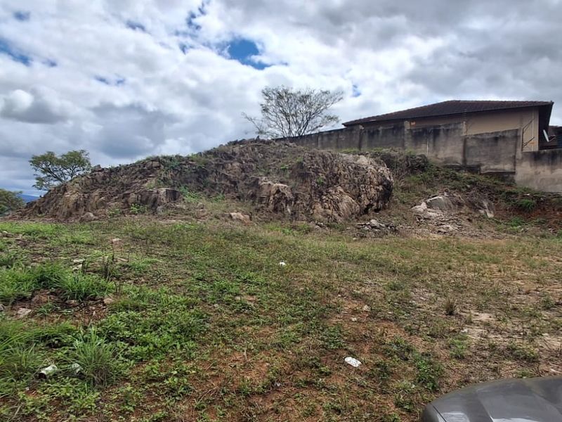 A view of the rear portion of the vacant residential land featuring a natural rock outcrop and a boundary retaining wall.