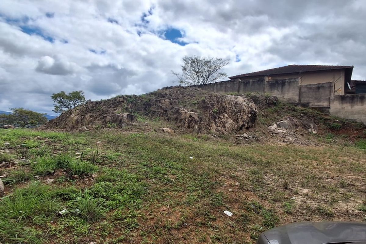 A view of the rear portion of the vacant residential land featuring natural rock formations and a boundary wall.