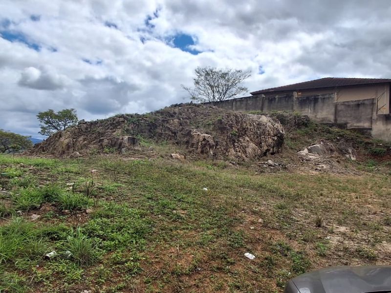 A view of the rear portion of the vacant residential land featuring natural rock formations and a boundary wall.