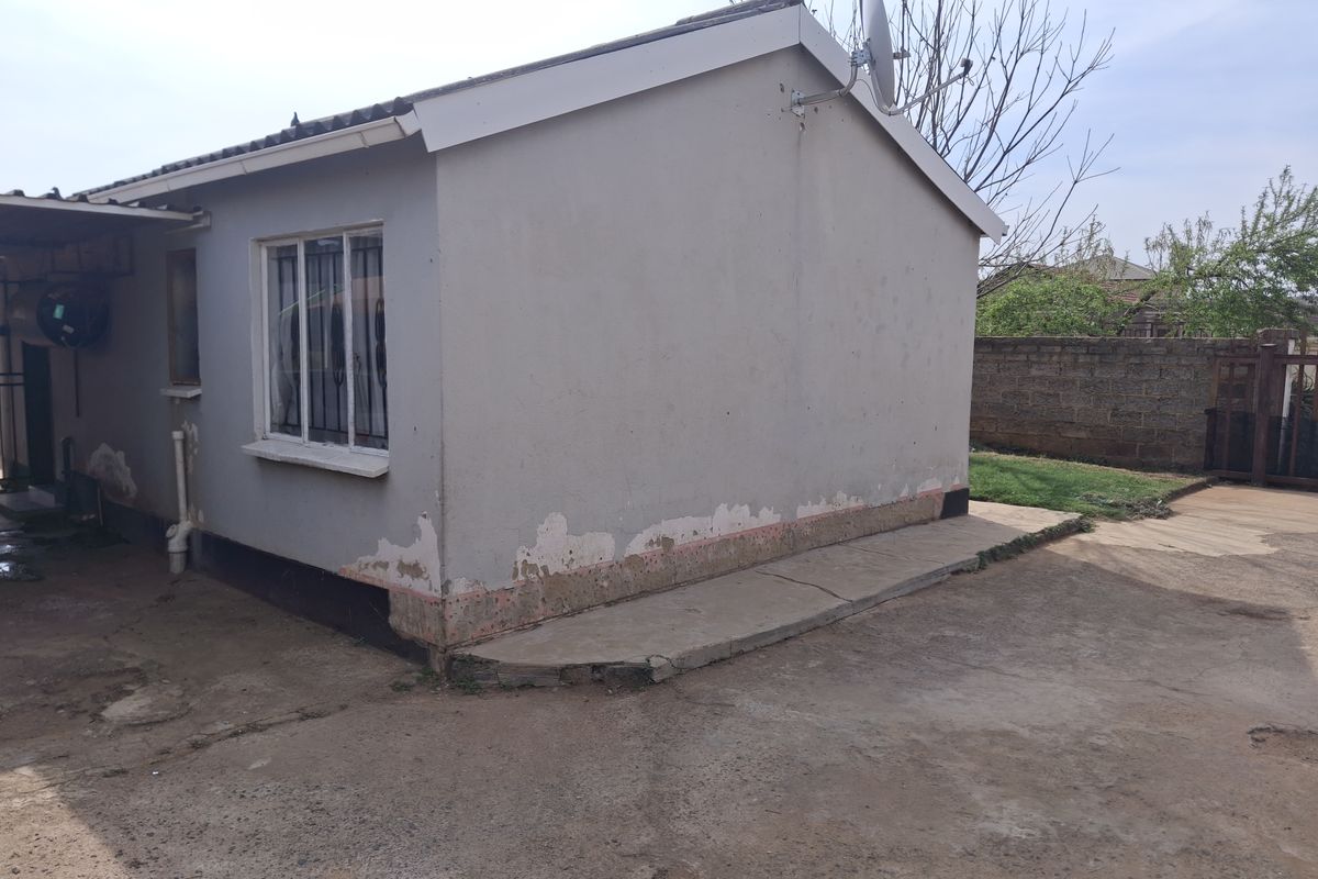 Rear view of the property showing exterior walls with peeling paint and a concrete apron requiring maintenance.