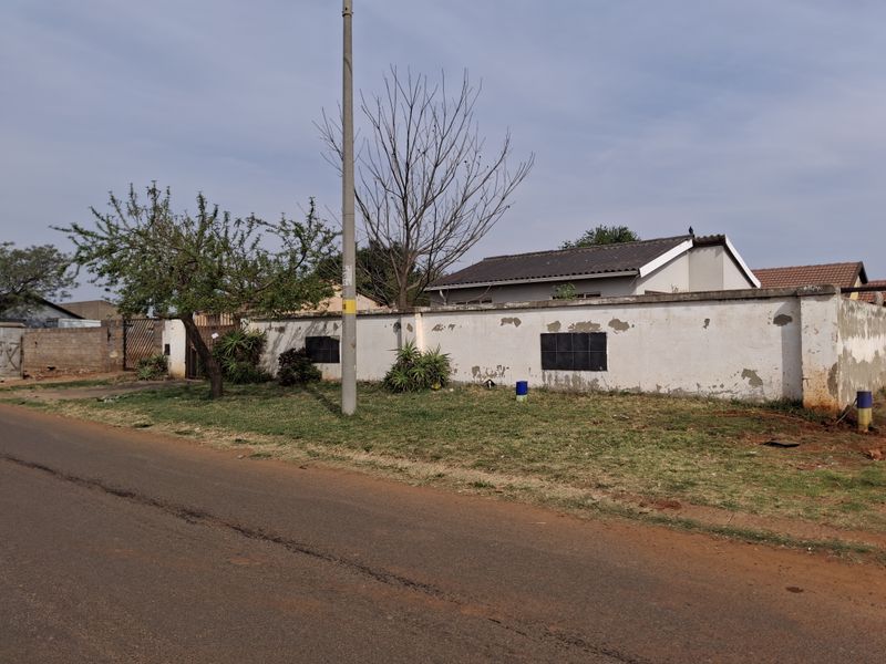 Street view of the property showing the boundary wall and a glimpse of the tiled roof structure.
