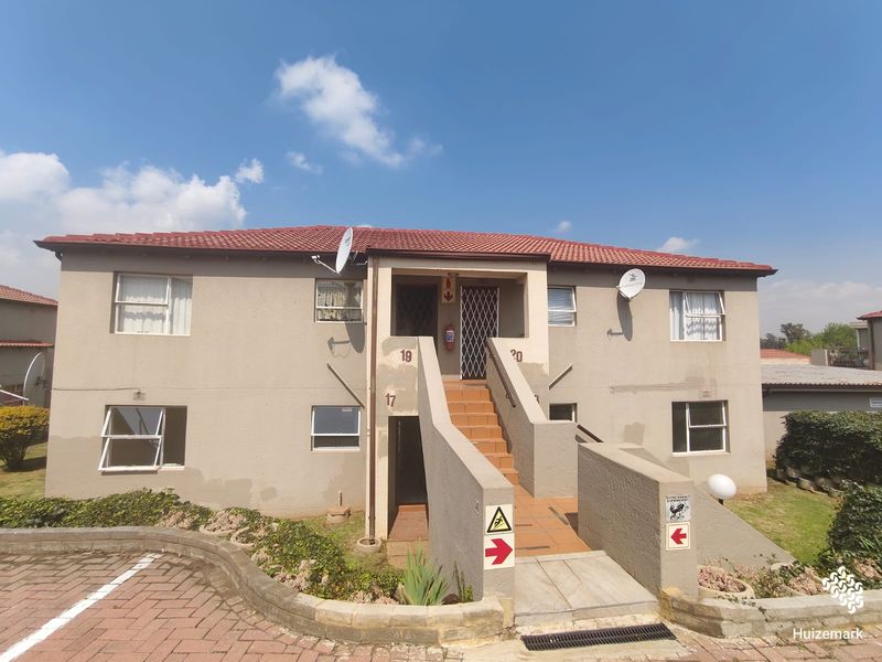 Front elevation of a two-story townhouse complex featuring a central staircase, tiled roof, and paved driveway access.