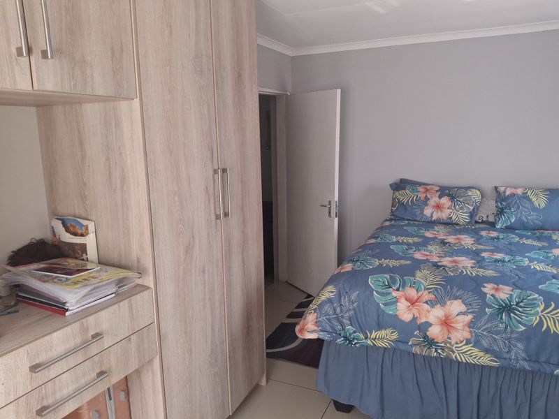 A well-maintained bedroom featuring light wood-finish built-in cupboards and neutral wall tones, providing ample storage and a clean, functional living space.