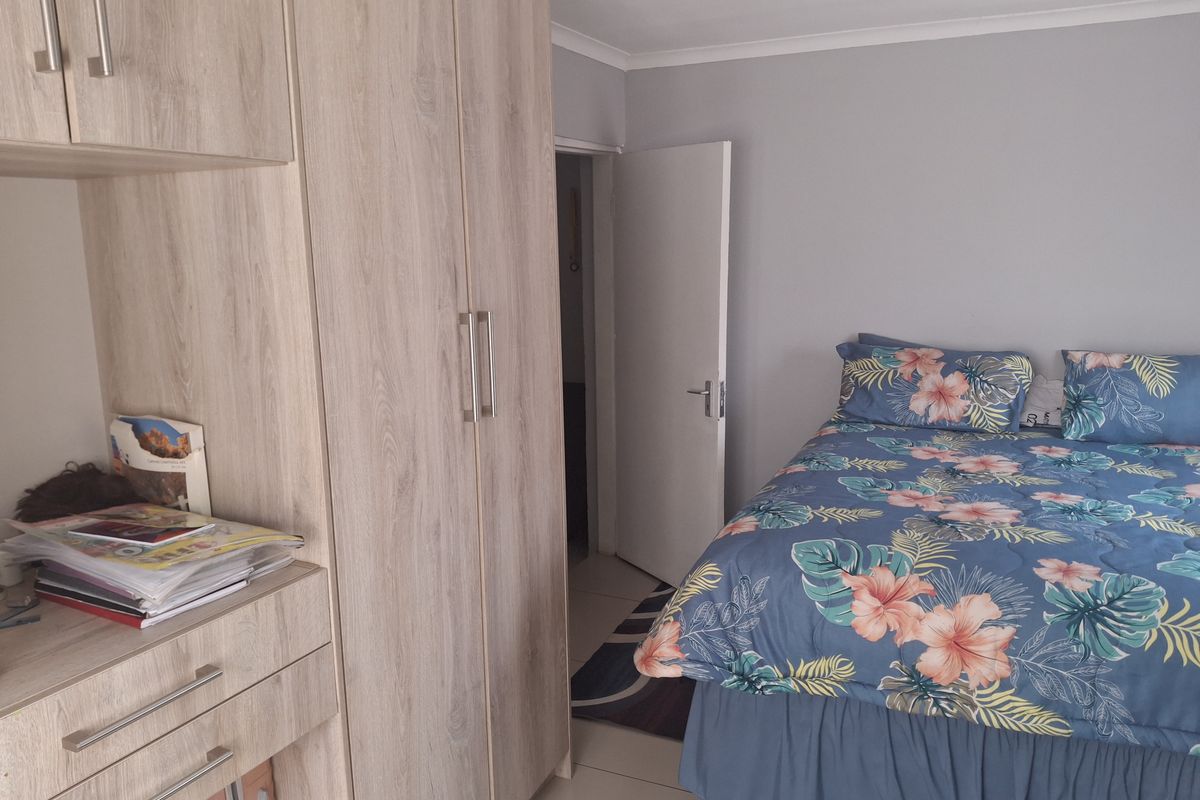 A well-maintained bedroom featuring light wood-finish built-in cupboards and neutral wall tones, providing ample storage and a clean, functional living space.