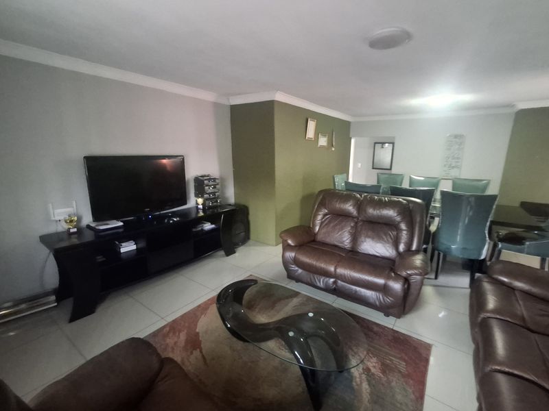 Spacious open-plan living and dining area featuring neutral tiled flooring and coved ceilings, providing a versatile layout for family living and entertaining.