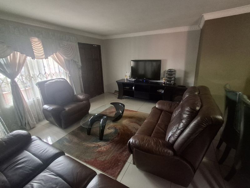 A living room featuring tiled flooring and decorative ceiling cornicing, providing a functional space for relaxation.