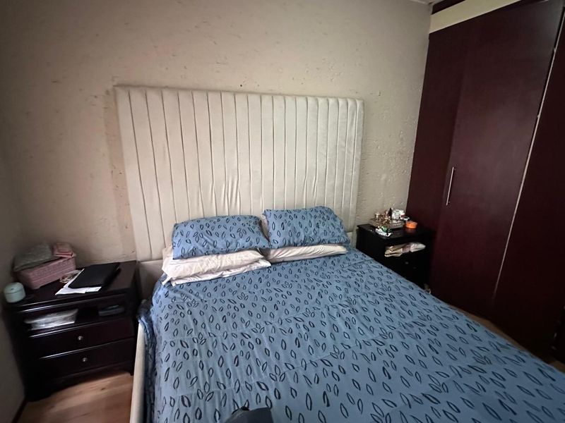 A bedroom featuring a built-in wardrobe and laminate flooring, with a textured wall finish.