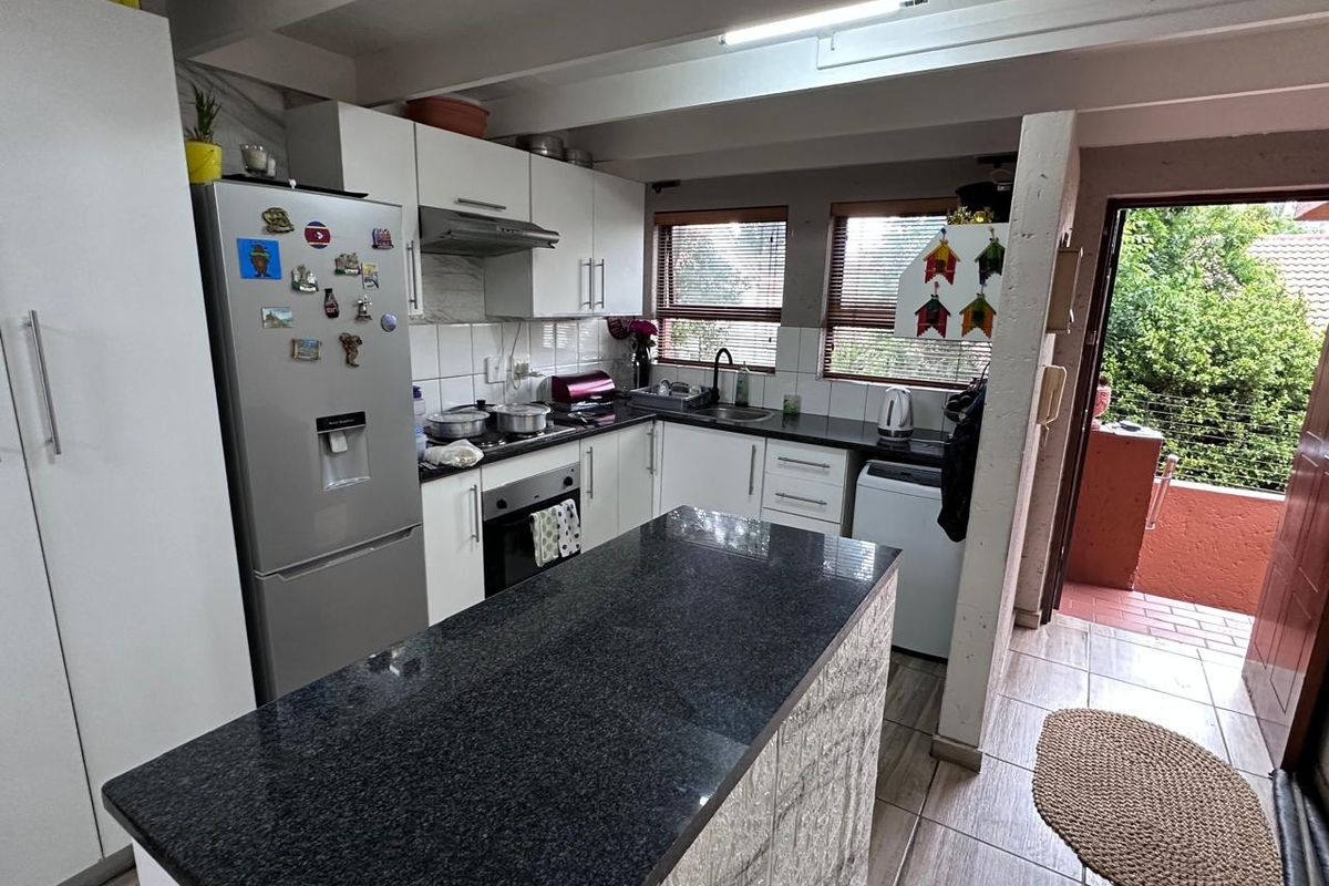 Functional kitchen featuring granite countertops, built-in cabinetry, oven, extractor fan, and direct access to an outdoor patio area.