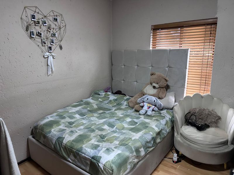 A bedroom featuring laminate flooring and venetian blinds, requiring cosmetic attention to the wall finishes.