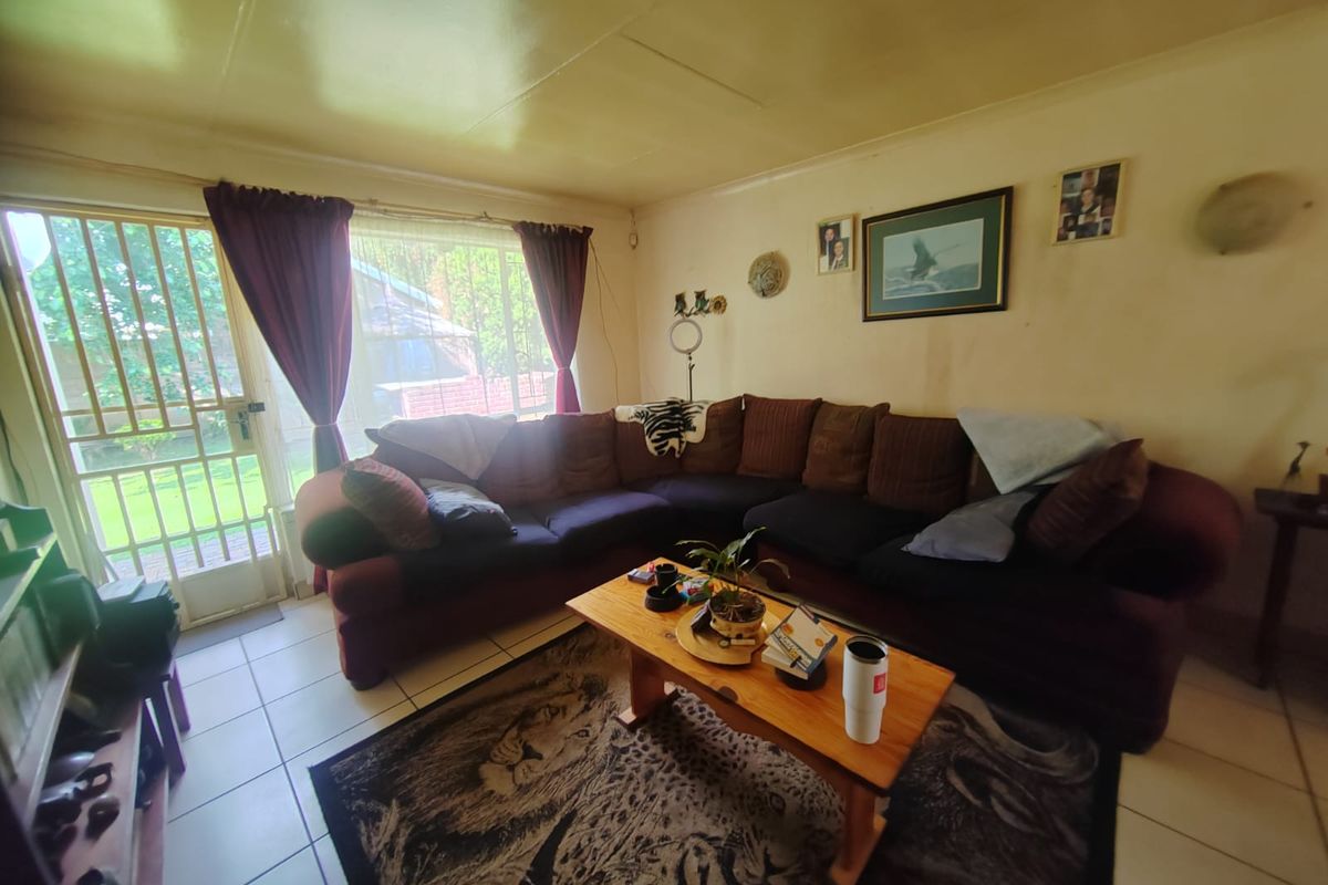 A living room featuring tiled flooring and a security gate leading to the exterior, with potential for cosmetic updates to the walls and ceiling.