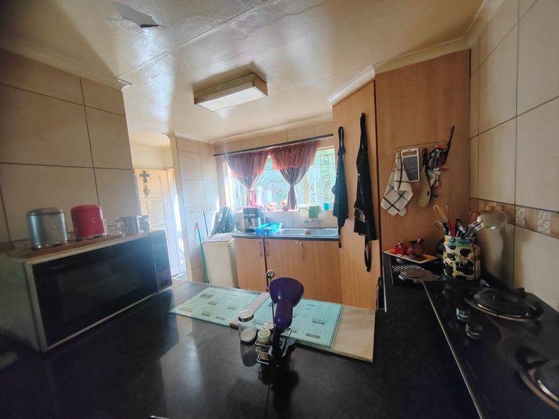 A functional kitchen featuring built-in cabinetry, a gas hob, and tiled splashbacks, offering a practical layout for daily meal preparation.