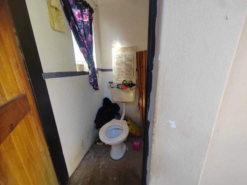 A small, dated bathroom featuring a standard toilet and cistern, requiring cosmetic updates and maintenance to improve its overall condition.