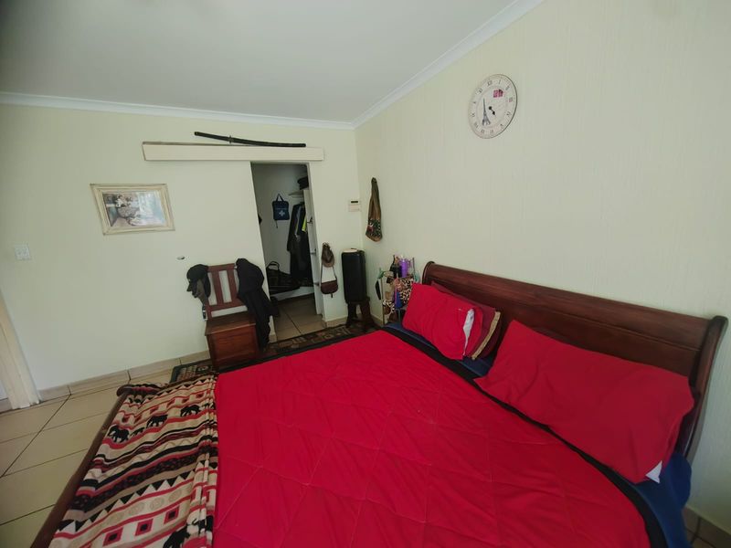 A standard bedroom featuring tiled flooring, a coved ceiling, and an integrated walk-in closet space.