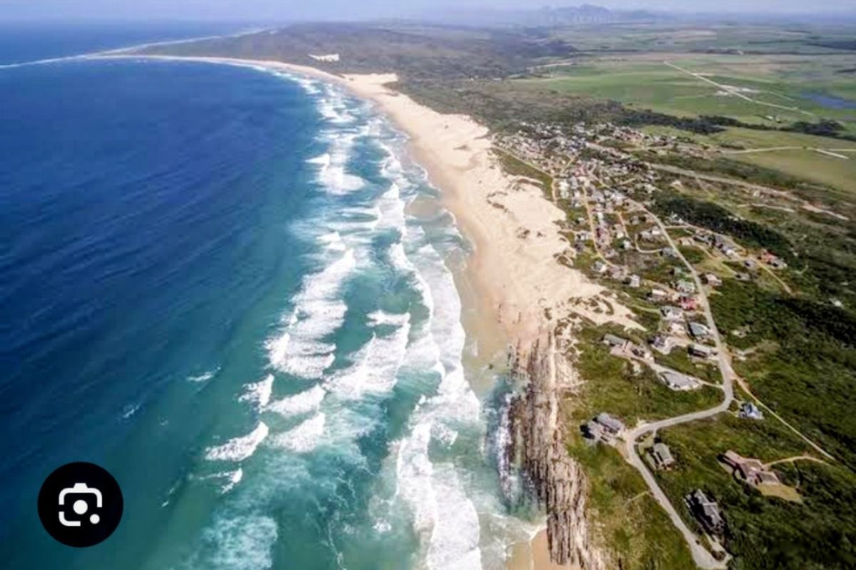 An aerial view of the coastal residential area, showcasing the expansive beach, oceanfront, and surrounding landscape.