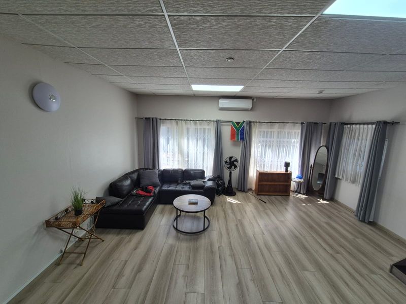 Spacious living room featuring modern laminate flooring, a suspended ceiling, and a wall-mounted split-system air conditioner.