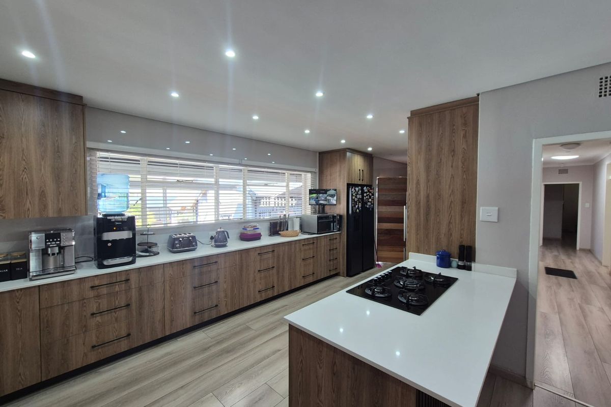 Modern kitchen featuring wood-grain cabinetry, quartz countertops, a central island with a gas hob, and recessed lighting.