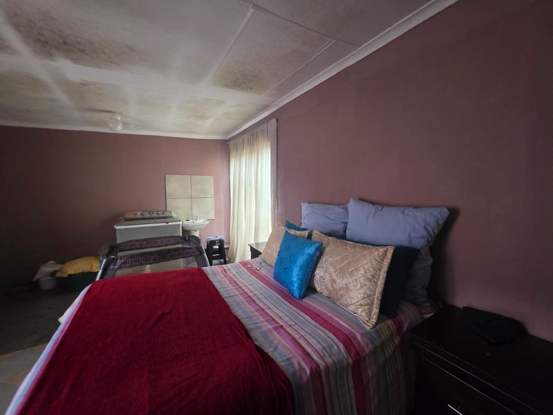 Bedroom featuring a built-in basin and tiled splashback, requiring ceiling repairs due to visible water staining and surface deterioration.