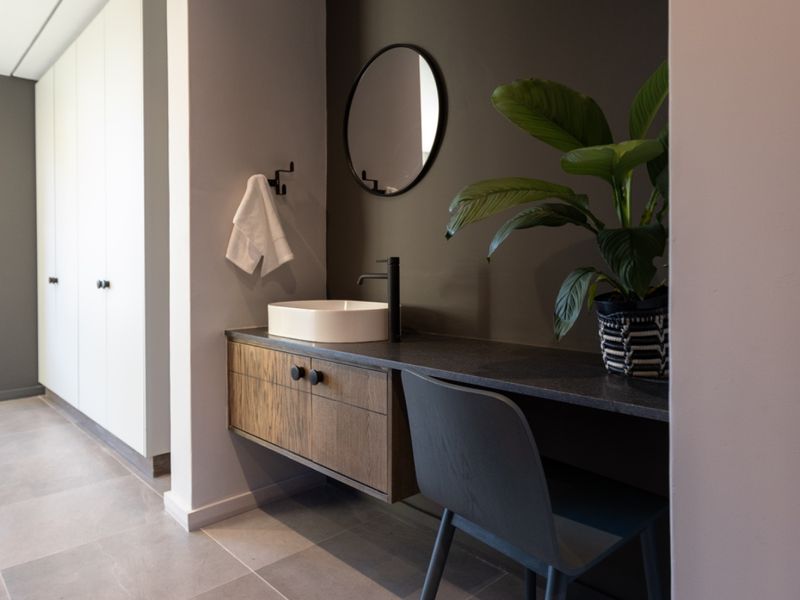 Modern bathroom featuring a floating vanity with a vessel sink, stone countertop, and sleek dark accent wall.