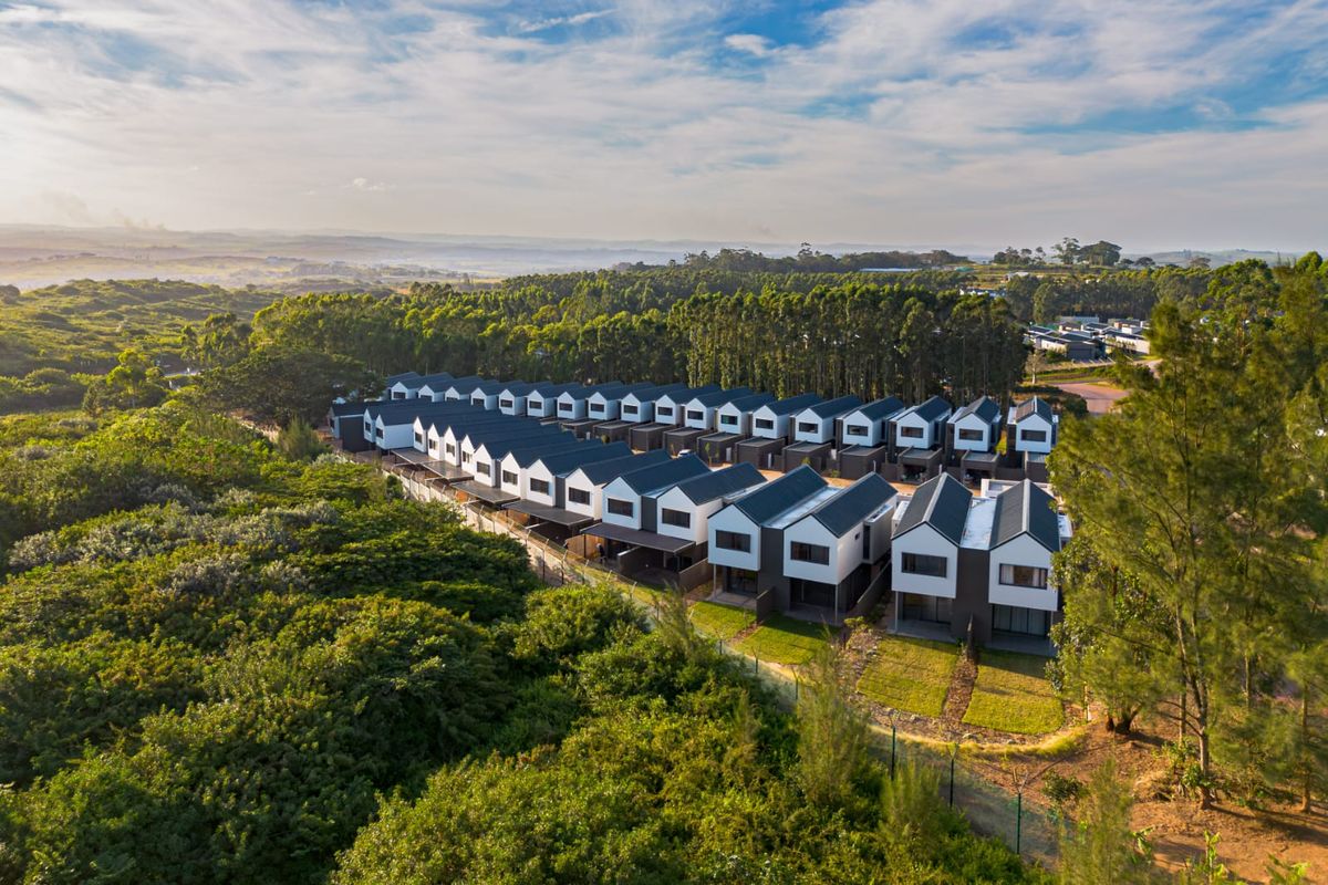 Aerial view of a modern townhouse complex development surrounded by lush greenery and natural landscape.