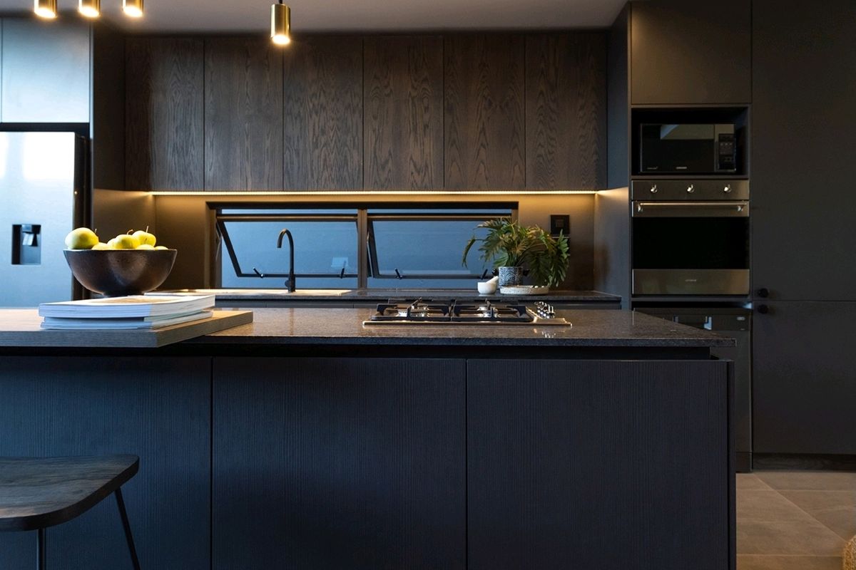 Modern, high-end kitchen featuring dark wood cabinetry, a stone island with integrated gas cooktop, built-in appliances, and sophisticated under-cabinet lighting.