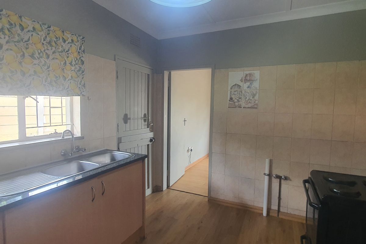 A functional kitchen featuring a double bowl sink, laminate countertops, tiled splashback, and wood-look flooring, offering a practical layout for daily use.