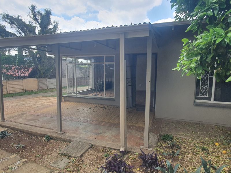 A covered outdoor patio area featuring paved flooring and security access, providing a functional space for outdoor relaxation.