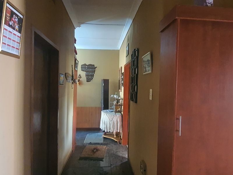 A functional residential hallway featuring tiled flooring, coving, and access to multiple rooms.