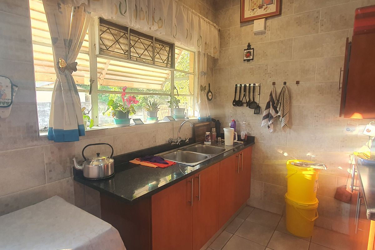 A functional kitchen featuring granite countertops, double basin sink, and tiled wall finishes with ample natural light from the window.