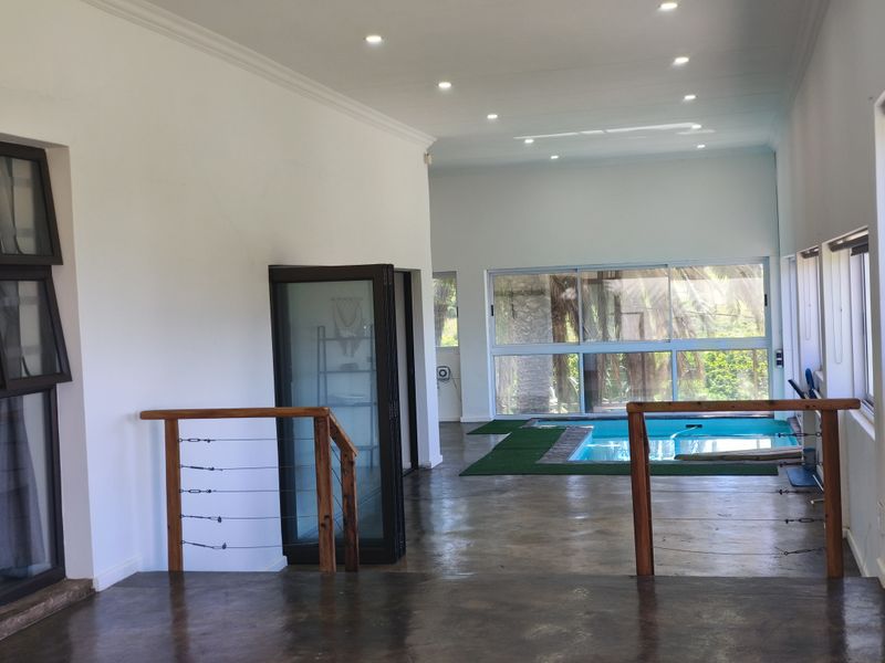 Spacious open-plan living area featuring polished concrete floors, recessed lighting, and direct indoor access to an integrated swimming pool.