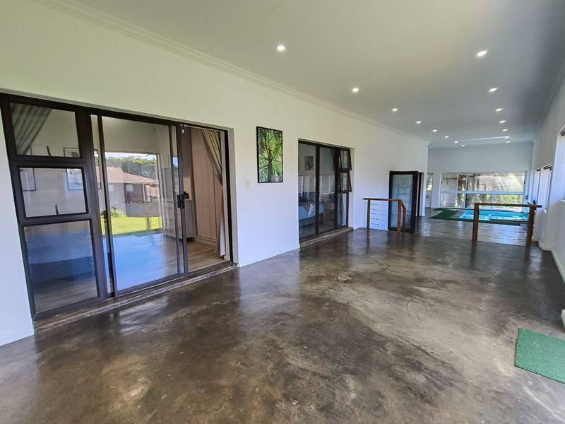 Spacious covered patio featuring polished concrete floors, recessed lighting, and large sliding glass doors providing seamless access to the interior and pool area.