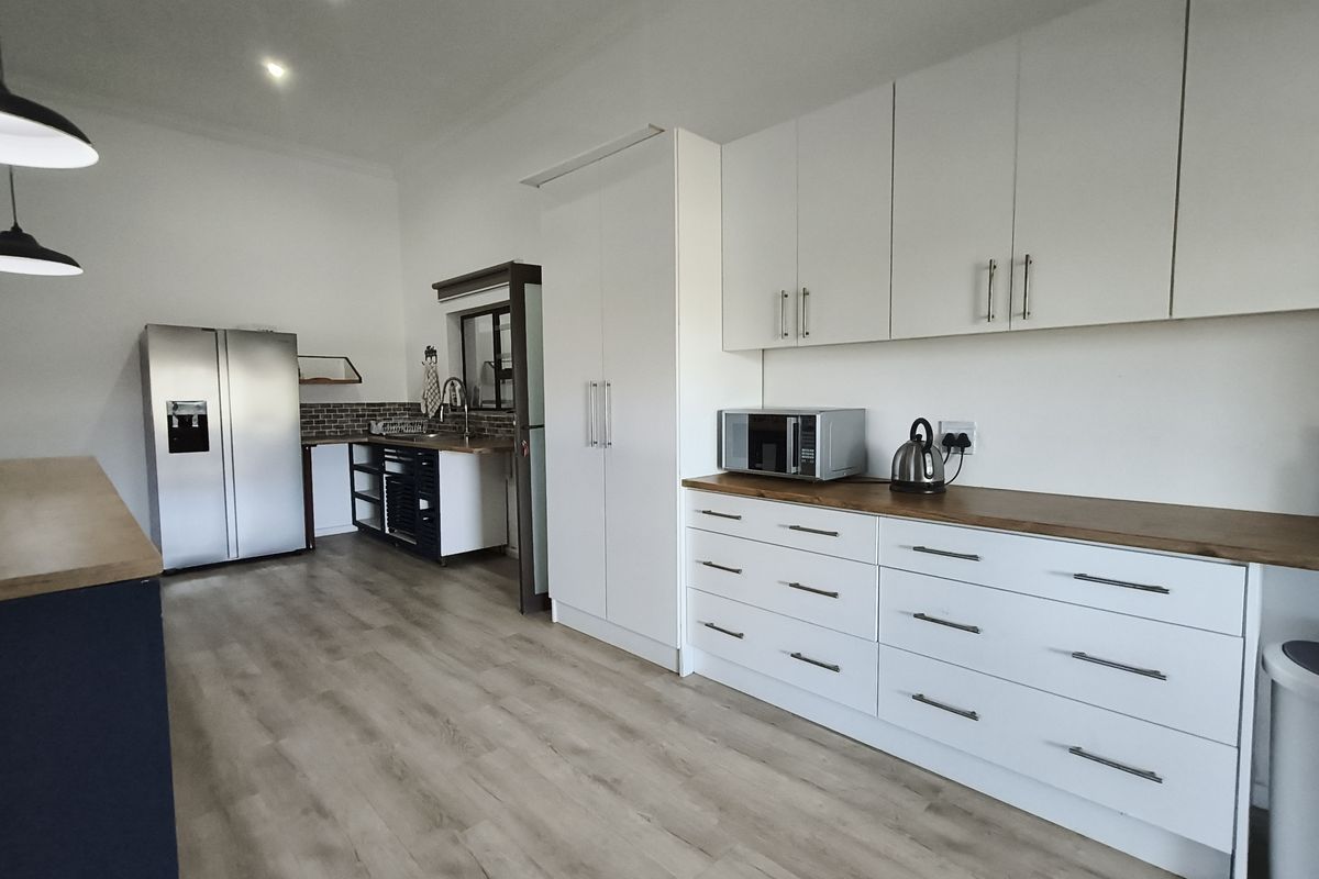 Modern kitchen featuring white cabinetry, warm wooden countertops, laminate flooring, and recessed lighting, offering a clean and functional workspace.