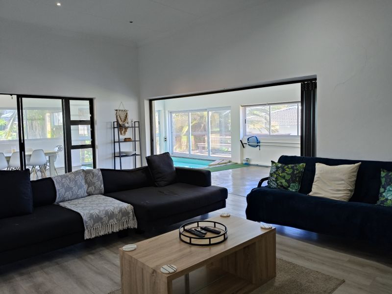 Spacious living area featuring large sliding glass doors that provide seamless indoor-outdoor flow to the pool area and patio.