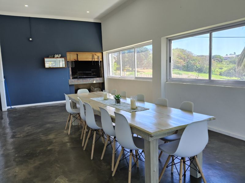 Spacious dining area featuring polished concrete floors, recessed lighting, large sliding windows, and a built-in indoor braai fireplace.