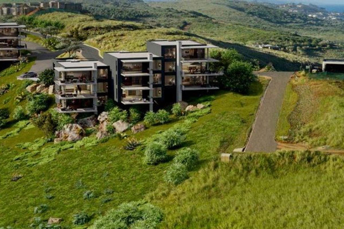An aerial perspective of a modern residential development situated on a coastal hillside, showcasing the architectural layout and proximity to the ocean.