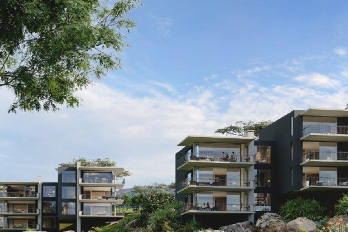 A modern apartment complex featuring multi-level units with expansive balconies and large glass facades set within a landscaped environment.